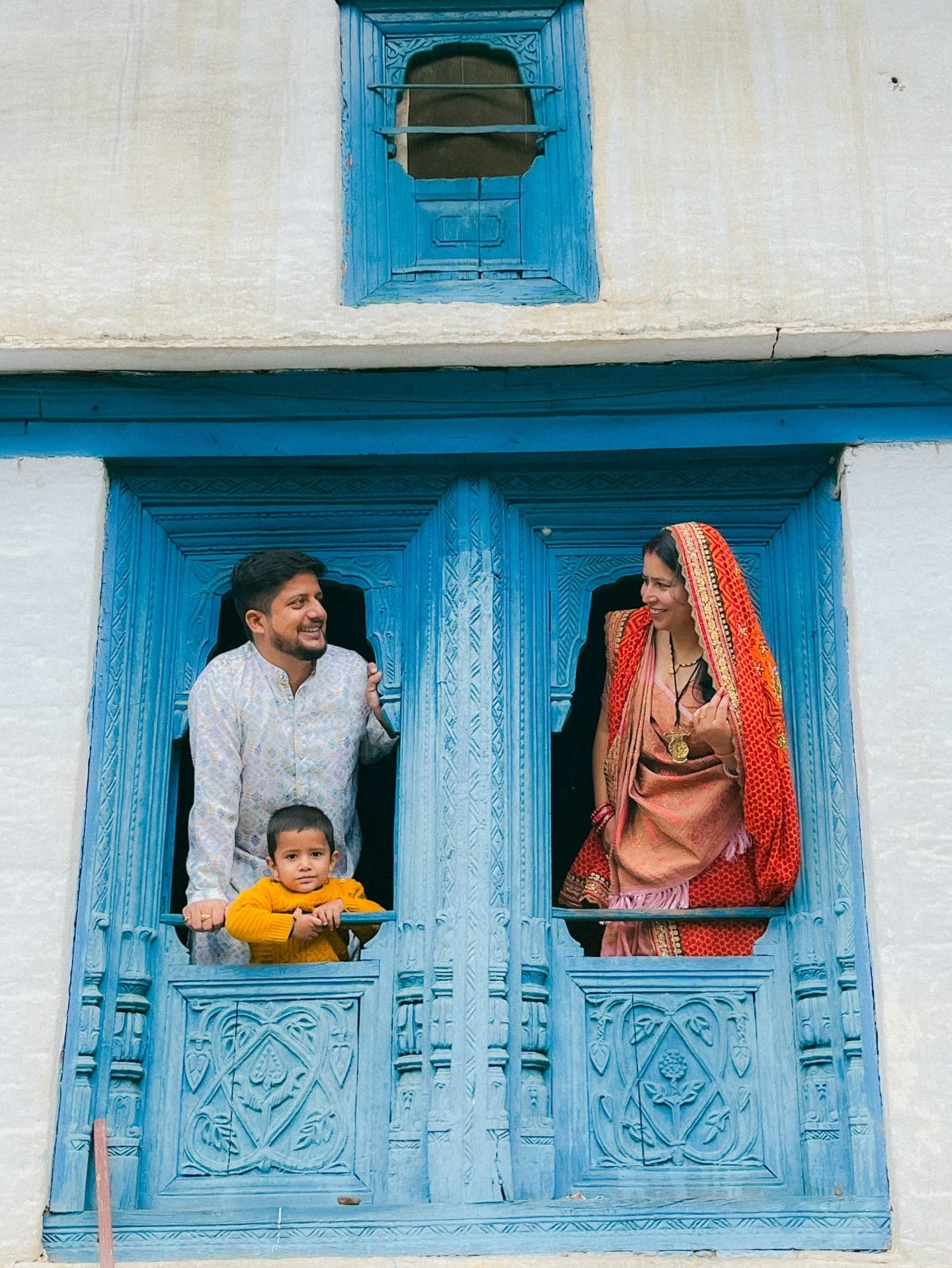 Family in traditional wedding attire at a carved blue balcony